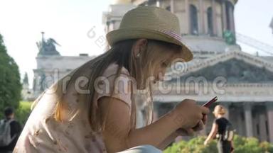 少女游客坐在城市街道上度假时用智能手机搜索信息。 技术、休闲